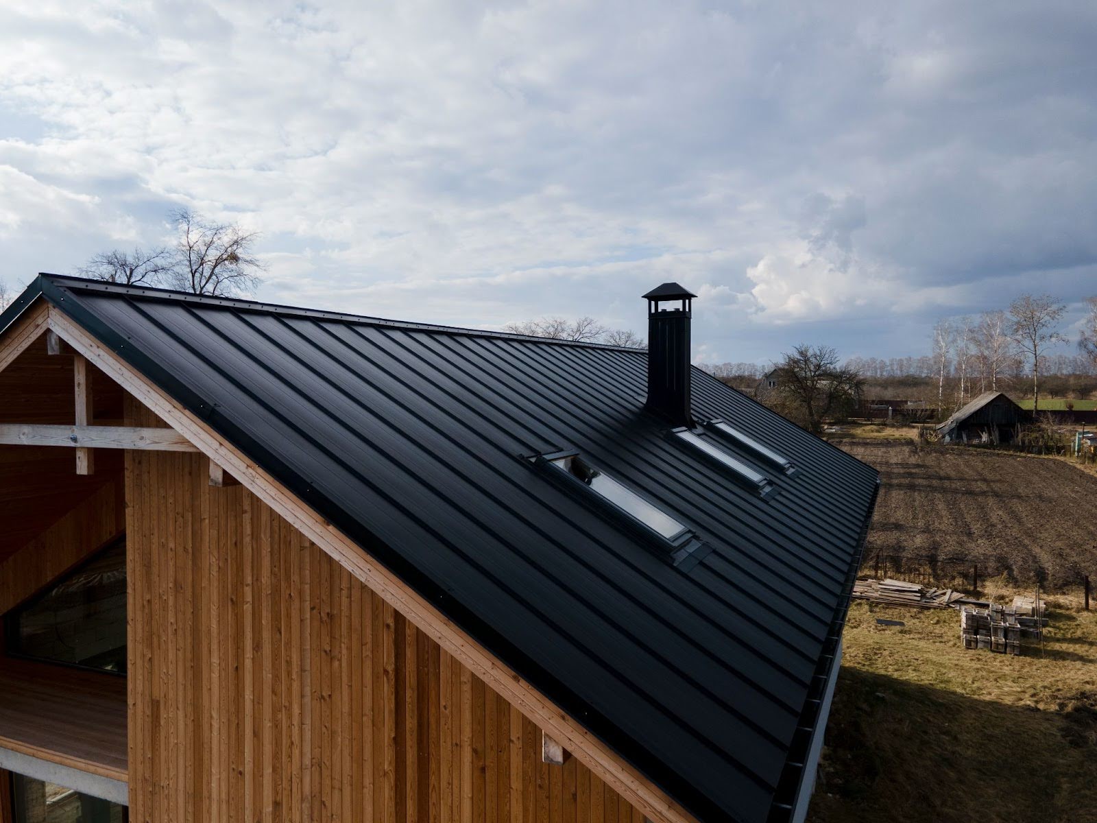 Modern black metal roof on a wooden home, illustrating quality roofing maintenance in Los Angeles with well-installed skylights and a clean, weather-resistant finish.